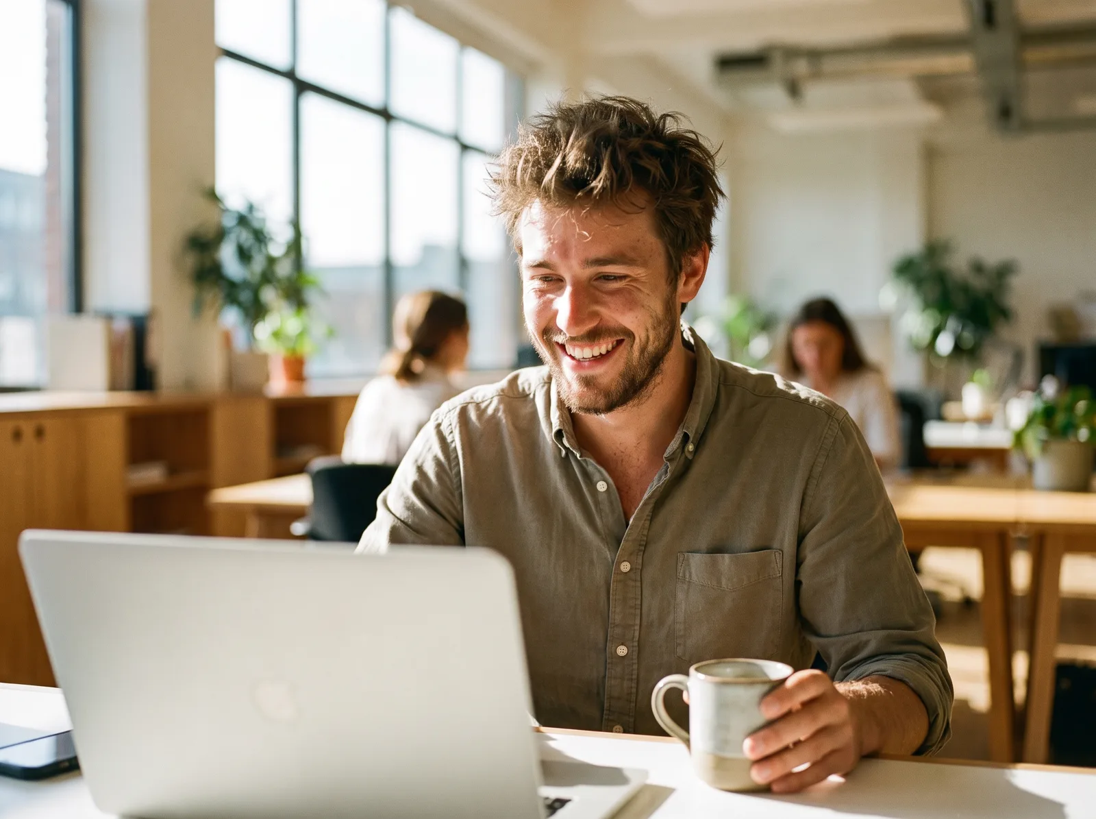 An insurance producer smiling at his laptop in a bright agency office